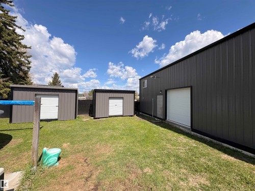 Large metal-clad auxiliary building featuring a white roll-up garage door and secondary entry - 5510 Railway Avenue, Glendon, AB - Outdoor