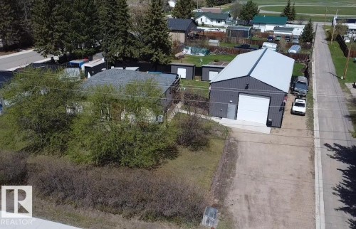 Detached metal-sided workshop featuring a large overhead door and a pedestrian entry door - 5510 Railway Avenue, Glendon, AB - Outdoor