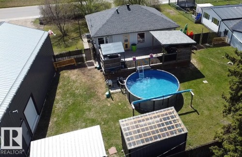 Expansive backyard featuring an above-ground pool, covered deck, and detached outbuilding with a metal roof - 5510 Railway Avenue, Glendon, AB - Outdoor With Above Ground Pool With Exterior