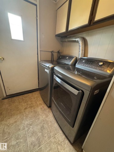Laundry area featuring a utility door with a small window, overhead cabinetry, and tile flooring - #46 4204 47 St, Wetaskiwin, AB - Indoor Photo Showing Laundry Room