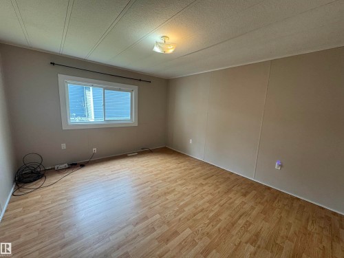 Spacious interior room featuring wood-finish flooring, neutral wall tones, and a large window providing natural light - #46 4204 47 St, Wetaskiwin, AB - Indoor Photo Showing Other Room