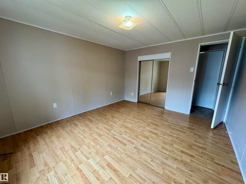 Spacious room featuring wood-finish flooring, paneled walls, and a ceiling-mounted light fixture - #46 4204 47 St, Wetaskiwin, AB - Indoor Photo Showing Other Room