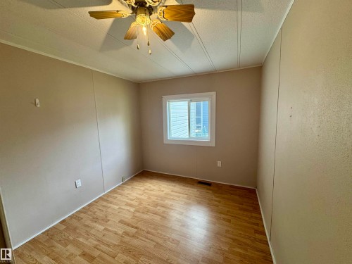 Room with wood-finish flooring, neutral wall paneling, and a single window with white trim - #46 4204 47 St, Wetaskiwin, AB - Indoor Photo Showing Other Room