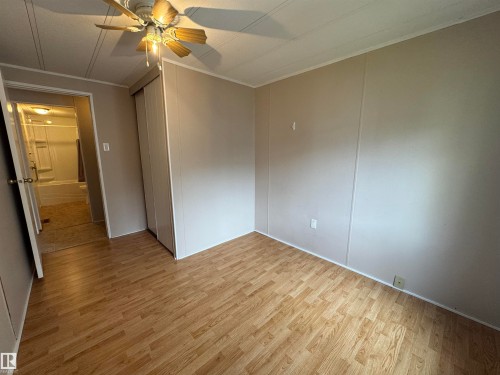 Interior room featuring wood-finish flooring, light-toned wall paneling, and a ceiling fan with integrated lighting - #46 4204 47 St, Wetaskiwin, AB - Indoor Photo Showing Other Room