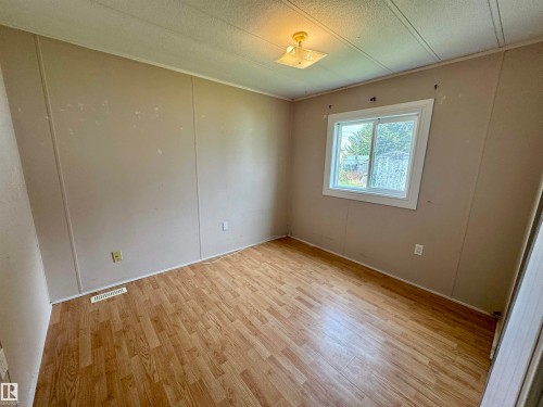 Room featuring wood-finish flooring, a white-framed window, and a ceiling-mounted light fixture - #46 4204 47 St, Wetaskiwin, AB - Indoor Photo Showing Other Room