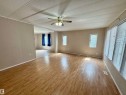 Spacious living area featuring wood-finish flooring, a ceiling fan, multiple windows with blinds, and neutral-toned wall paneling - #46 4204 47 St, Wetaskiwin, AB  - Indoor Photo Showing Other Room 