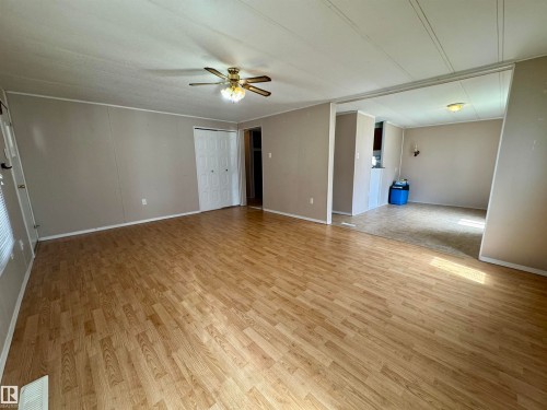 Spacious interior featuring wood-finish flooring, a ceiling fan with light fixture, and neutral wall tones - #46 4204 47 St, Wetaskiwin, AB - Indoor Photo Showing Other Room