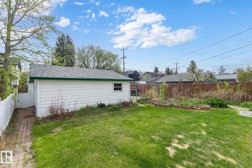 Spacious backyard featuring a white detached garage with green trim, a manicured lawn, a white picket fence, and raised garden beds - 10823 130 Street, Edmonton, AB - Outdoor