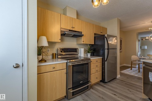 Kitchen featuring light wood-finish cabinetry, stainless steel appliances, light countertops, and wood-finish flooring - 41 8304 11 Avenue, Edmonton, AB - Indoor Photo Showing Kitchen