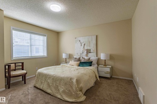 Carpeted room with a large window featuring horizontal blinds, a white window frame, and neutral-toned walls - 41 8304 11 Avenue, Edmonton, AB - Indoor Photo Showing Bedroom