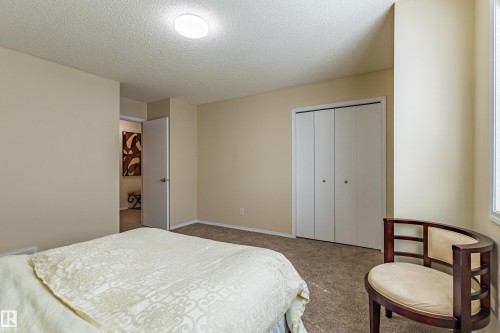 Carpeted room with neutral-toned walls, a flush-mount ceiling light, and a white bi-fold closet - 41 8304 11 Avenue, Edmonton, AB - Indoor Photo Showing Bedroom