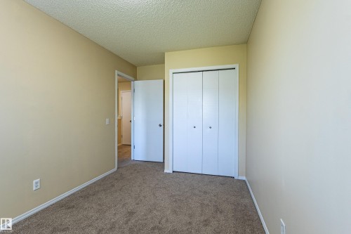 Carpeted room featuring neutral-toned walls, white baseboards, and a bi-fold closet door - 41 8304 11 Avenue, Edmonton, AB - Indoor Photo Showing Other Room