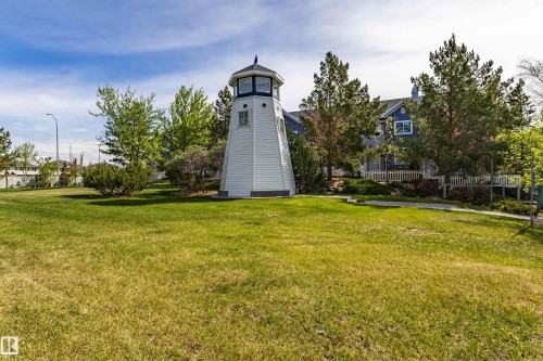 Lighthouse-inspired structure amidst a grassy expanse, featuring a white paneled exterior, a dark blue cap, and multiple window openings - 41 8304 11 Avenue, Edmonton, AB - Outdoor