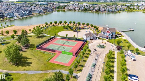 Expansive waterfront setting featuring multiple tennis courts, a sandy beach area, and a community building with an adjacent dock - 41 8304 11 Avenue, Edmonton, AB - Outdoor With Body Of Water With View
