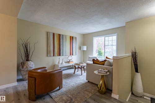 Light-toned walls complement wood-finish flooring throughout this living area - 41 8304 11 Avenue, Edmonton, AB - Indoor
