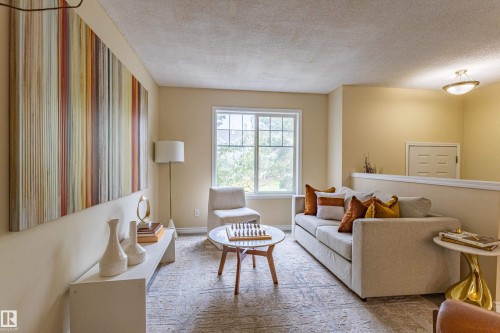 Bright living area featuring a large window, neutral wall paint, textured ceiling, and a built-in half-wall partition - 41 8304 11 Avenue, Edmonton, AB - Indoor