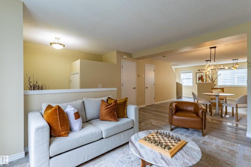 Open-concept living area with light-toned walls and wood-finish flooring - 41 8304 11 Avenue, Edmonton, AB - Indoor Photo Showing Living Room