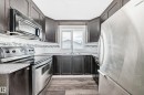 Kitchen featuring dark wood-finish cabinetry, stainless steel appliances, and wood-finish flooring - 8615 42A Avenue, Edmonton, AB  - Indoor Photo Showing Kitchen With Double Sink 