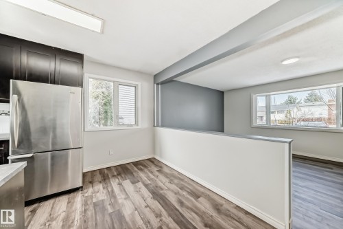 Open-concept living space featuring wood-finish flooring, stainless steel appliances, dark wood cabinetry, and multiple windows - 8615 42A Avenue, Edmonton, AB - Indoor