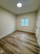 Neutral-toned room featuring contemporary wood-finish flooring, a white trim window, and a modern ceiling light fixture - 