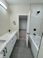 Contemporary bathroom featuring a double vanity with quartz-finish countertops and integrated sinks - 