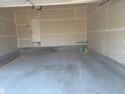 Spacious garage featuring a concrete floor, unpainted drywall walls, and a white interior door - 