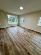 Spacious room featuring wood-finish flooring, neutral-toned walls, and multiple windows providing natural light - 