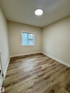 Room featuring wood-finish flooring, neutral wall paint, and white trim - 