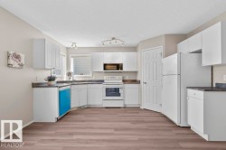 U-shaped kitchen featuring white cabinetry, dark countertops, and wood-finish flooring - 