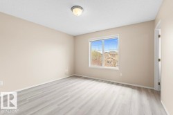 Room featuring wood-finish flooring, neutral wall tones, white trim, and a window with grid patterns - 