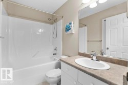 Bathroom featuring a white integrated tub and shower unit with a brushed nickel showerhead and faucet - 
