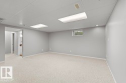 Spacious room featuring light-colored carpeting, neutral painted walls, and a drop ceiling with recessed lighting - 