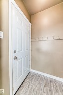 Panel door with chrome hardware, light wood-finish flooring, white baseboards, and wall-mounted coat hooks - 
