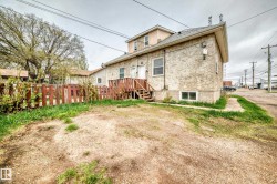 Rear exterior featuring stucco siding, multiple window units, and a basement window - 