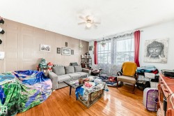 Living area featuring wood-finish flooring, a ceiling fan, and panel-style accent wall - 