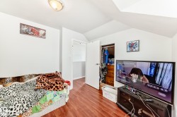 Room featuring wood-finish flooring, white painted walls, and an angled ceiling - 