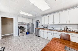 Kitchen featuring white cabinetry with brushed nickel hardware, wood-finish countertops, and wood-finish flooring - 