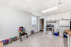 Kitchen space featuring wood-finish flooring, white cabinetry, and stainless steel appliances - 