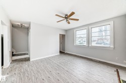 Open concept living area featuring wood-finish flooring, light grey walls, and a ceiling fan - 