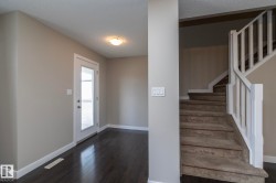Entryway featuring dark wood-finish flooring, light grey painted walls, white trim, and a glass-paneled door - 