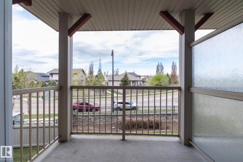 Covered outdoor balcony featuring a textured concrete floor, light-toned metal railing, and a privacy panel with textured glass - 117 Callaghan Drive Sw, Edmonton, AB - Outdoor With Exterior