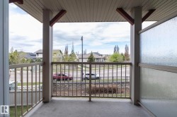 Covered outdoor balcony featuring a textured concrete floor, light-toned metal railing, and a privacy panel with textured glass - 