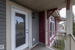 Private exterior balcony featuring a white glass-paneled door, gray horizontal siding, red shake siding, white window trim, and a cream-colored railing - 