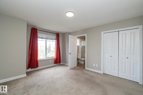 Carpeted room featuring a double window, overhead flush-mount lighting, bi-fold closet doors, and light grey wall paint with white baseboards - 117 Callaghan Drive Sw, Edmonton, AB - Indoor