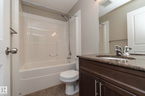 Bathroom featuring a dark wood-finish vanity with a stone-look countertop, integrated sink, and chrome faucet - 117 Callaghan Drive Sw, Edmonton, AB - Indoor Photo Showing Bathroom