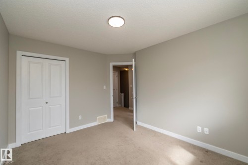 Carpeted room featuring light gray walls, white baseboards, and a bi-fold closet door - 117 Callaghan Drive Sw, Edmonton, AB - Indoor