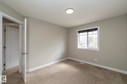 Neutral tone wall paint with white trim, carpeting, a single window with blinds, and an overhead flush-mount light fixture - 