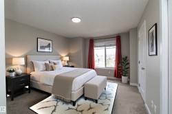 Bedroom featuring a neutral color palette, ceiling-mounted light fixture, window with red drapery, and a white six-panel interior door - 