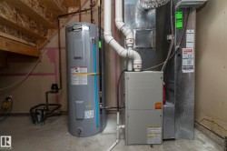 Mechanical room featuring a water heater, furnace, and exposed ductwork - 
