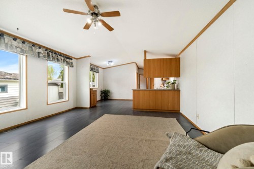 Spacious living area featuring dark wood-finish flooring, white paneled walls, and multiple large windows - 49 Rim Road Nw, Edmonton, AB - Indoor